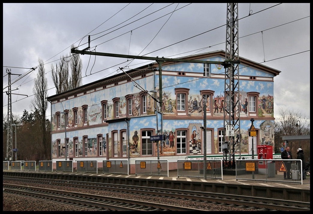Der Bahnhof von Bad Wilsnack zeigt viele unterschiedliche Fassaden Bilder. Er dient zwar nicht mehr dem DB Bahnbetrieb. Ich konnte dort ein Reise Infozentrum erkennen. Auch werden dort Appartements als Bahnhofsquartier angeboten. 
Durch die Fassaden Malerei ist das Gebäude ein echter Hingucker! Die Aufnahme entstand am 6.12.2024.