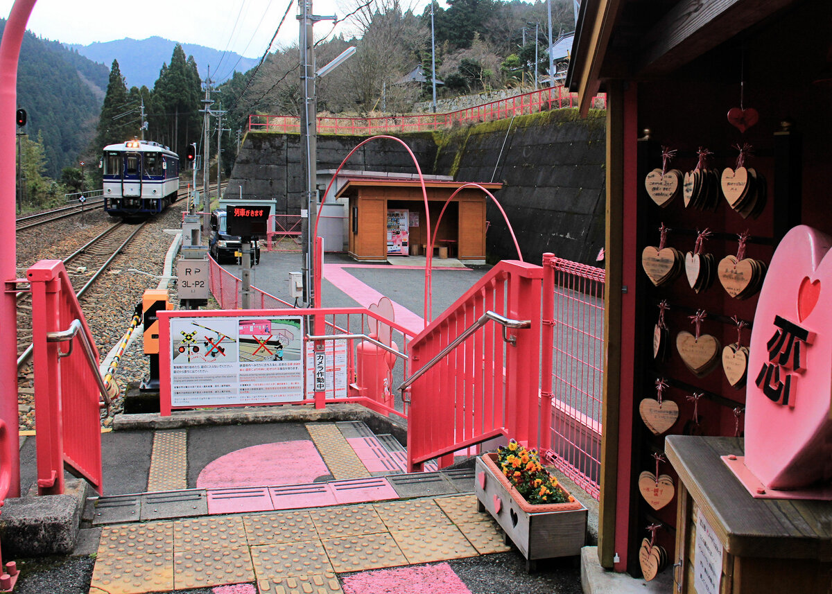 Der Bahnhof Koi Yamagata an der Chizu Kyûkô Privatbahn: Einfahrt des Lokalzug-Triebwagens 3506. Im Vordergrund das  Herz-Monument , hinten in der kleinen Hütte unter anderem der Automat, wo man eine zu beschriftende kleine Tafel kaufen kann. 11.März 2020 