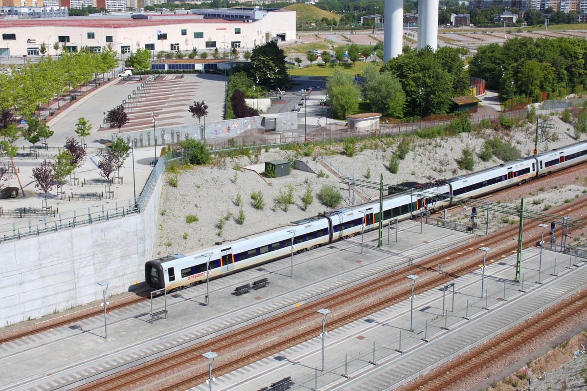 Der Bahnhof Malmö Hyllie ist eine Verkehrsstation mit vier Gleisen die auf zwei Richtungsbahnsteige verteilt sind. Auf den äußeren Gleisen verkehren die Züge in Richtung Dänemark und in der Mitte verlaufen die Gleise nach Trelleborg und Simrishamn. Am 06.07.2017 ist ein Öresundzug auf dem Weg in Richtung Kopenhagen.