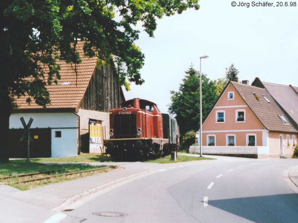 Der Bahnhof Mühlhausen liegt etwa 200 Meter östlich vom Ort. Das Gleis führt danach mitten durch den Ort, wobei kurz nacheinander vier Bahnübergänge folgen.  (V100 1023 am 20.6.98) 