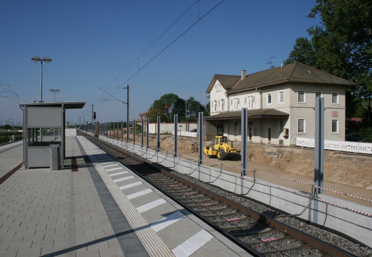 Der Bahnhof Schliengen whrend der Umbauphase am 07.05.2011: links der neu erstellte Mittelbahnsteig mit den verschwenkten Gleisen der Rheintalbahn, rechts – zwischen entstehender Lrmschutzwand und ehemaligem Empfangsgebude – die Trasse zum Katzenbergtunnel.