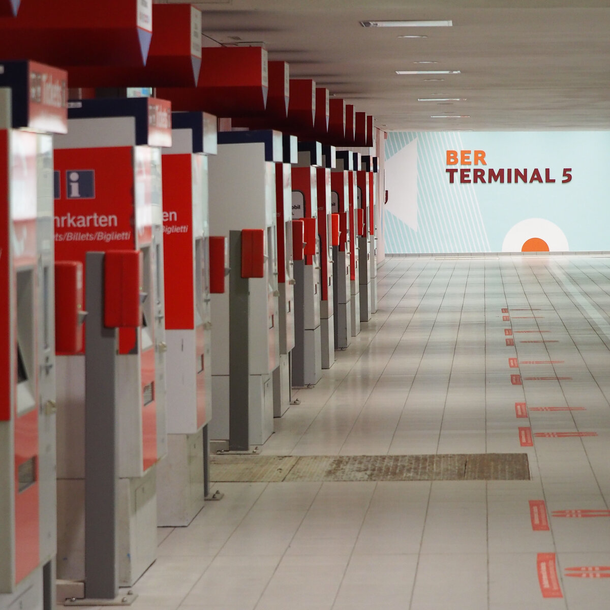Der Bahnhof Schönefeld aka Flughafen BER – Terminal 5. 
Blick entlang der vielen ungenutzen Fahrkartenautomaten im Quertunnel mit Blick Richtung Süden (Ausgang Flughafen Terminal 5).

Berlin, der 06.08.2021