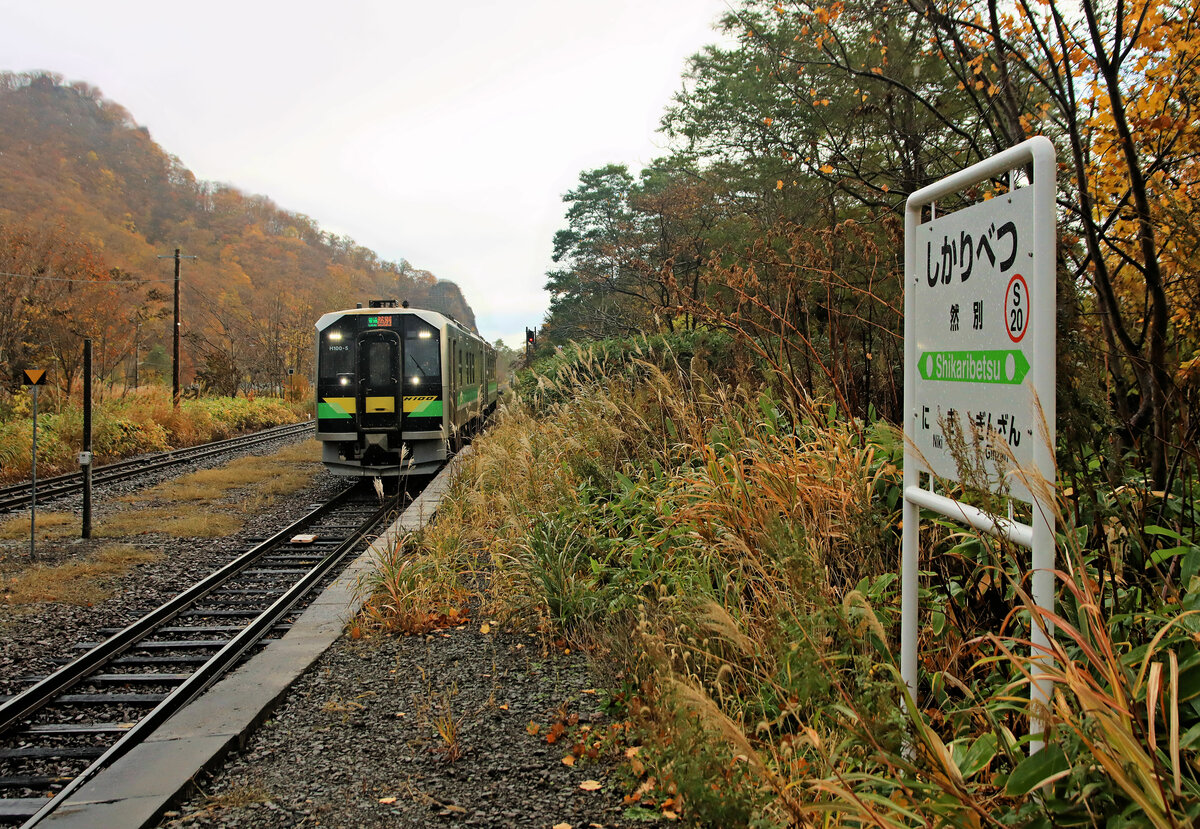 Der Bahnsteig von Shikaribetsu im Morgennebel, an der früheren Hauptstrecke vom Fährhafen Hakodate nach Sapporo. Die Expresszüge fahren heute einen Umweg, der aber flach ist und hohe Geschwindigkeiten zulässt. Bald wird die Strecke hier eingestellt, wenn der Hochgeschwindigkeitszug Shinkansen bis Sapporo eröffnet ist. Bild: Einfahrt der beiden Regionaltriebwagen H100-5 und H100-12, 29.Oktober 2022
