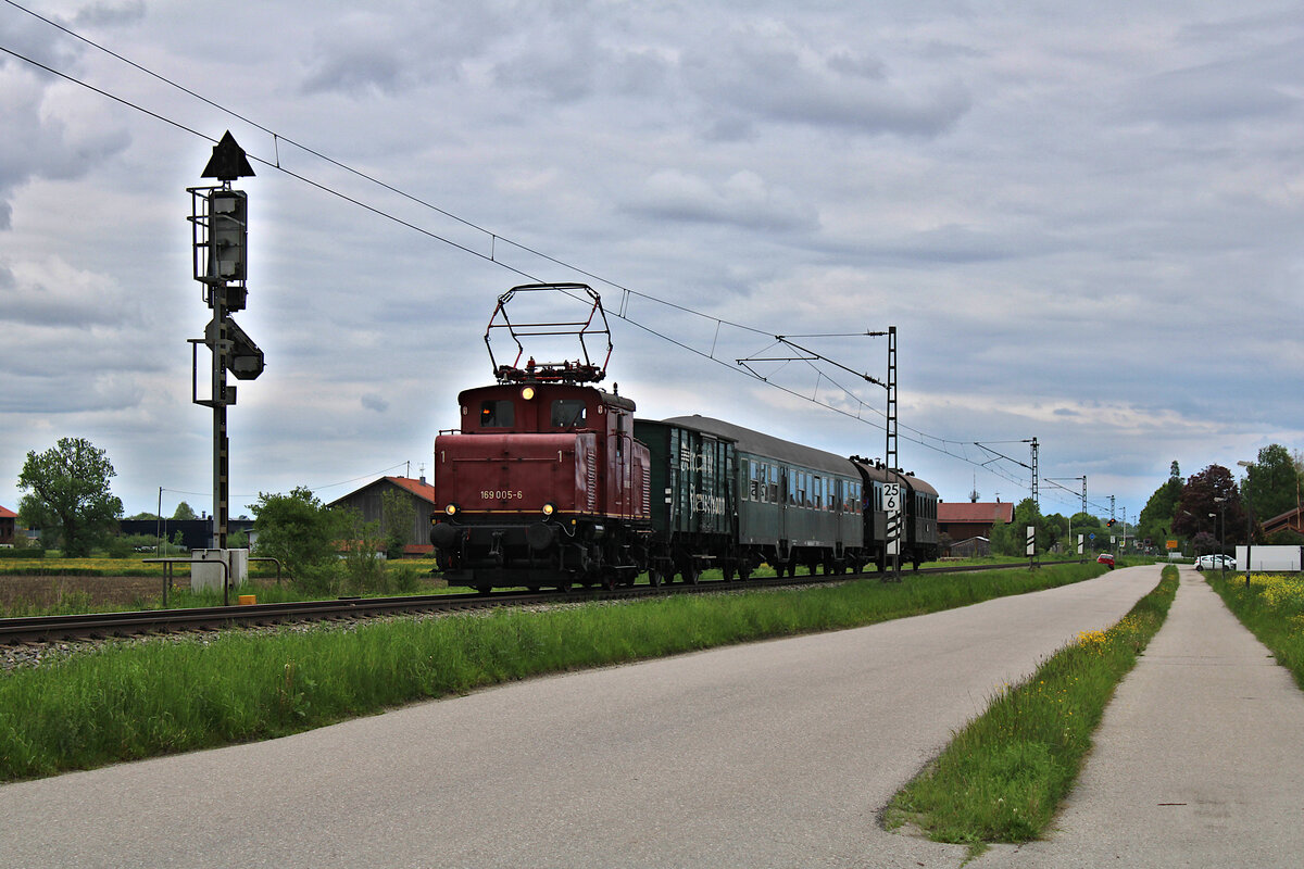 Der Bayerische Localbahn Verein ist mit E69 005 und einem Sonderzug unterwegs zurück von Prien am Chiemsee nach München Ost und passiert hier gerade bei dichter Wolkendecke das Einfahrsignal von Heuberg. (18.05.2023)