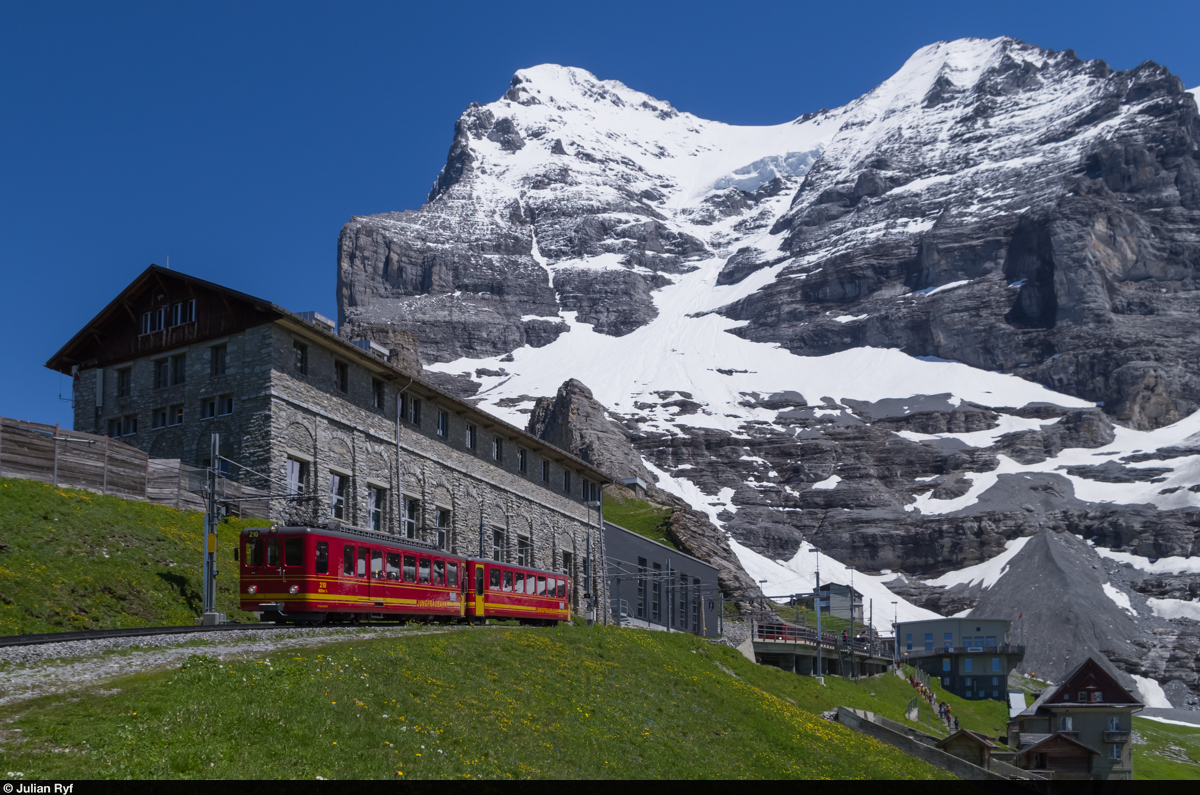 Der BDhe 2/4 210 der Jungfraubahn fährt am 24. Juni 2015 talwärts aus der Station Eigergletscher aus. Im Hintergrund der Eiger aus ungewohnter Perspektive.