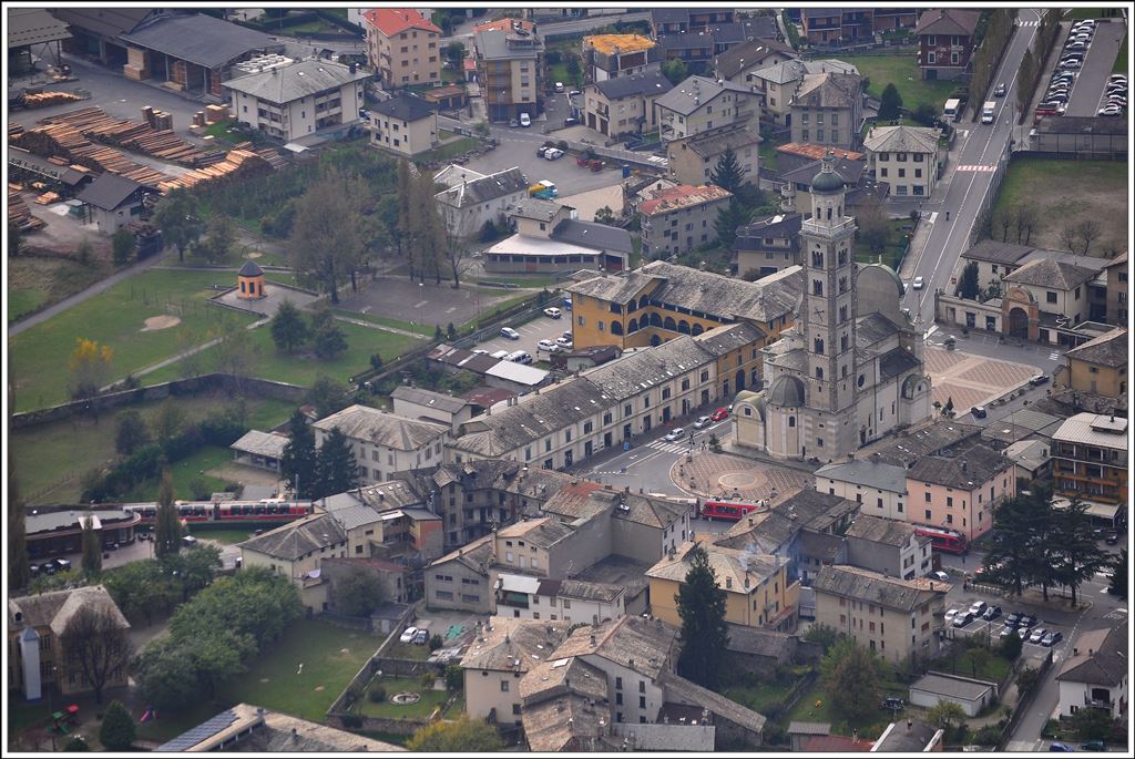 Der Berninaexpress 960 nach Davos Platz überquert soeben die belebte Kreuzung bei der Basilica Madonna di Tirano. (25.10.2014)