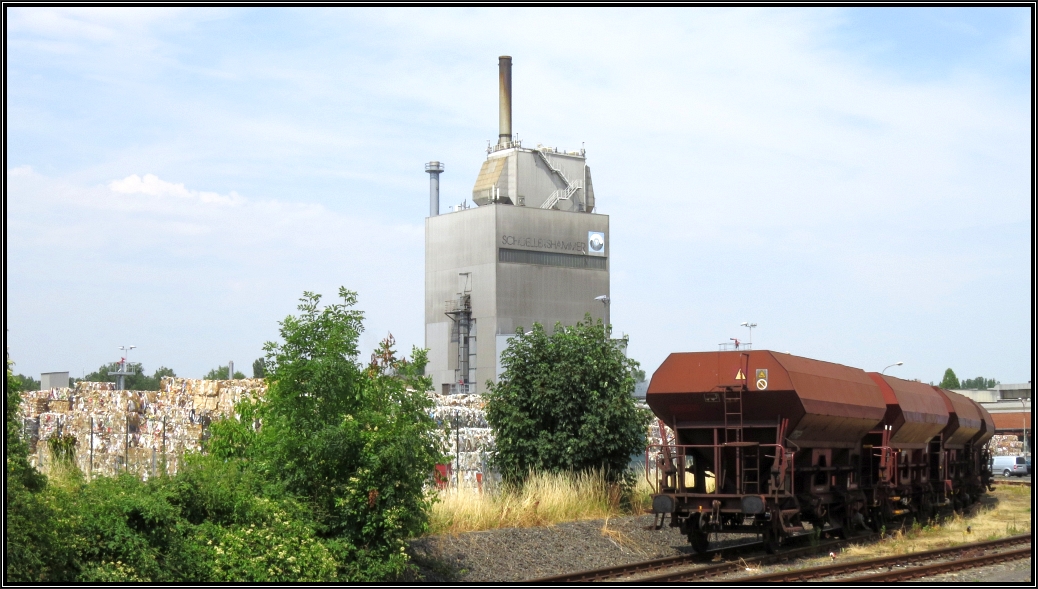 Der Blick auf die Fabrikkulisse der Firma Schoellerhammer (Papierverarbeitung) in Lendersdorf bei Düren. Ein paar abgestellte Schüttgutwagen stehen im Anschlußgleis der Firma.Momentaufnahme vom 05.Juli 2015.