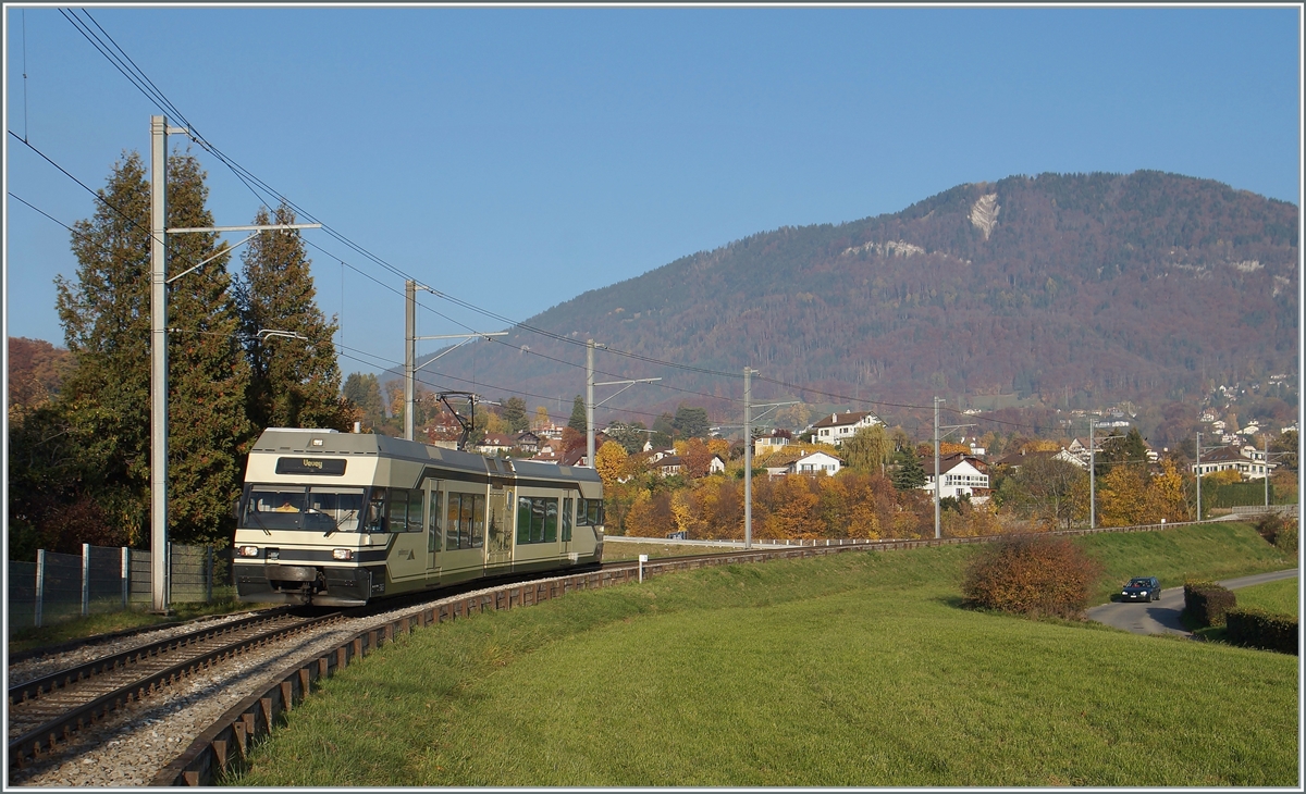 Der CEV MVR GTW Be 2/6 7004  Montreux  ist als Regionalzug auf dem Weg nach Vevey und erreicht den Halt Château d'Hauteville. 
Im Hintergrund der Les Pleiades, auf dessen Gipfel zwar die Strecke der CEV führt, der CEV MVR GTW aber aufgrund des fehlenden Zahnradantriebes nicht fahren kann, so dass den vier GTW-Triebwagen nur die Adhäsion Strecke der CEV Vevey -Blonay (- Chamby) als Einsatzgebiet bleibt. Dazu kommen noch Einsätze im Vorortverkehr ab Montreux bis Les Avants. Da die Zahnradtriebwagen bereits ein fortgeschrittenes Alter erreicht haben. dürfte dies wohl der Grund gewesen sein, die CEV Flotte mit ABeh 2/6 Triebzügen zu vereinheitlichen und die noch fast neuen CEV Be 2/6 weiterzugeben, wobei der hier zu sehende Be 2/6 7004  Montreux  zur  MIB bzw. in der Folge zur Zentralbahn bzw. SBB kommen sollte.

2. November 2015