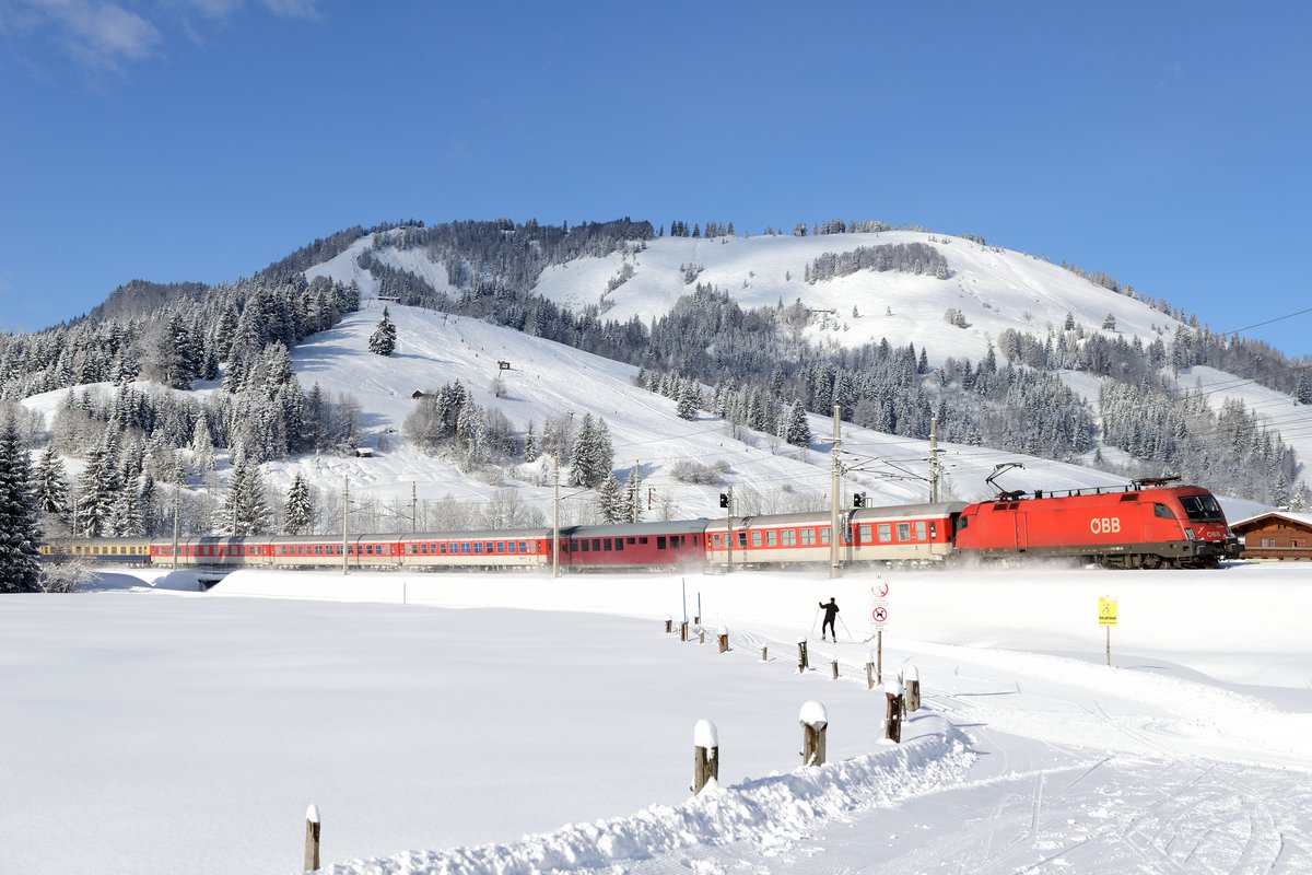 Der D 13813 AlpenExpres von Amsterdam nach Bischofshofen konnte am 31. Januar 2015 bei Hochfilzen abgelichtet werden. Geführt wurde der Turnuszug von 1116.181, die den Namen  Hanspeter  auf der Front trägt. Die Wintersport-Reisenden können sich beim Blick auf die Langlaufloipe und den Skilift zur Oberkantalm schon auf ihren Urlaub einstimmen.
 
