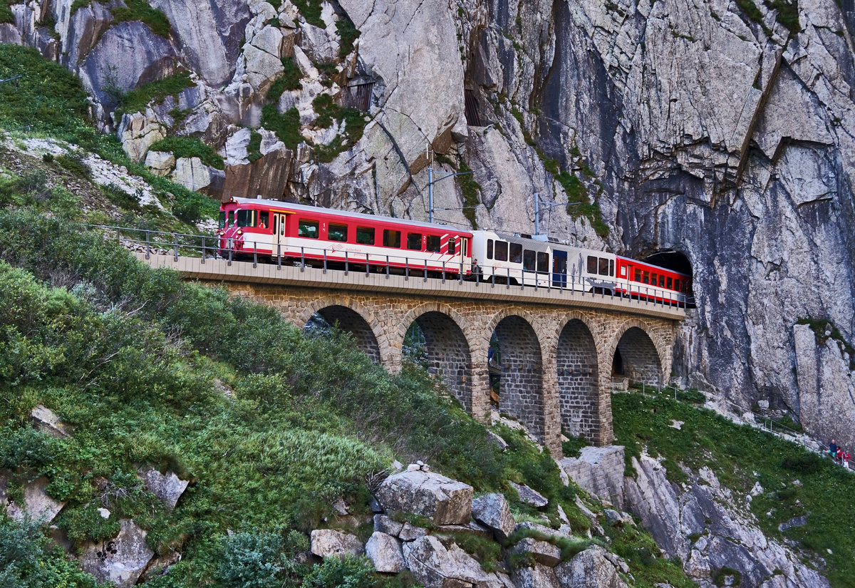 Der von der Deh 4/4 93 geschobene R 663 (Göschenen - Andermatt), taucht mit dem Steuerwagen voraus aus dem Jostbach-Tunnel in der Schöllenenschlucht auf.
Aufgenommen am 20.7.2016.