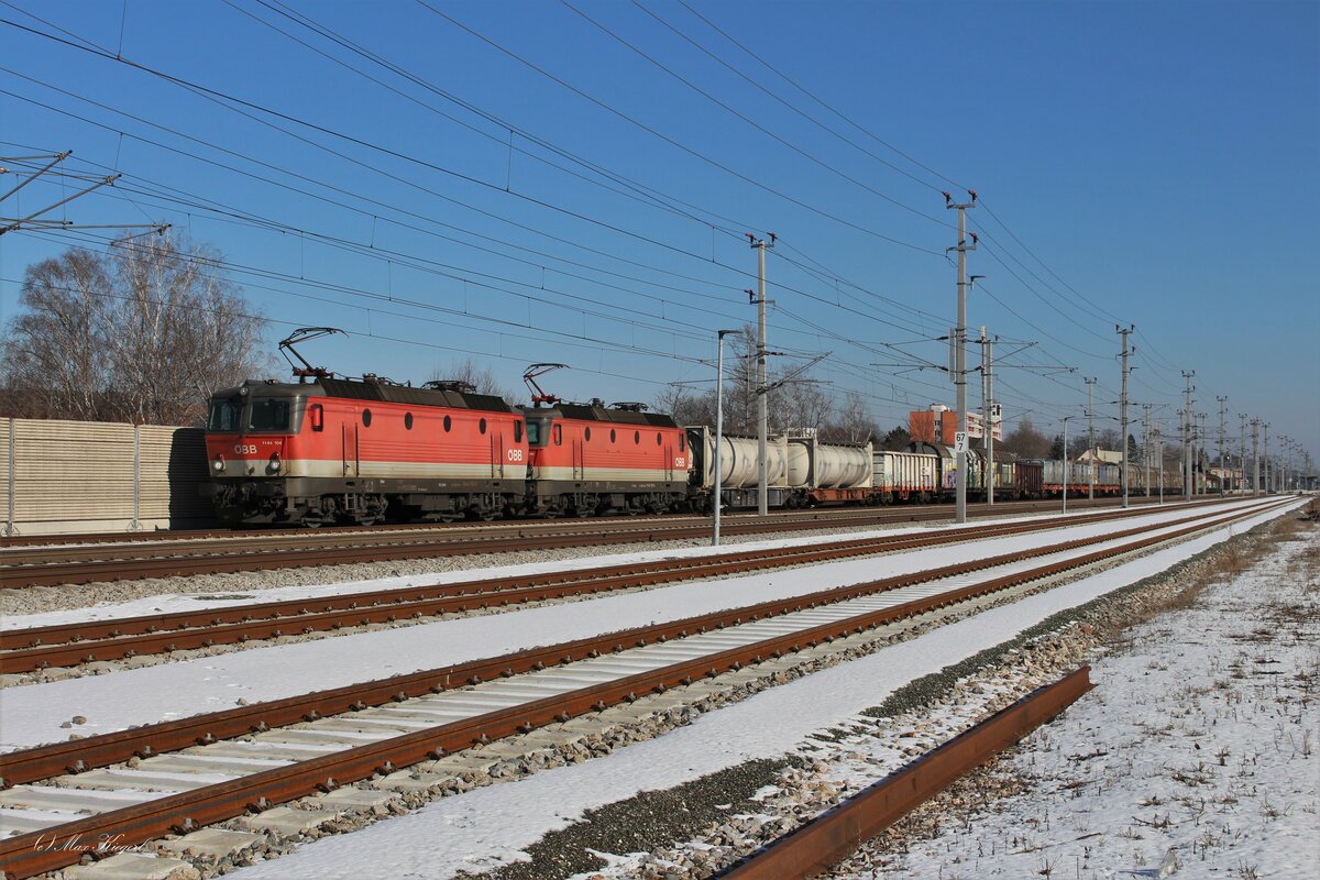 Der DG54703 von Wien Zvb nach Graz Vbf wartet am sonnigen 7.2.2023 im Bahnhof Ternitz auf die Vorfahrt eines Railjets bevor die 1144 104 und die 1144 110 den Zug seinem Ziel entgegen bringen.