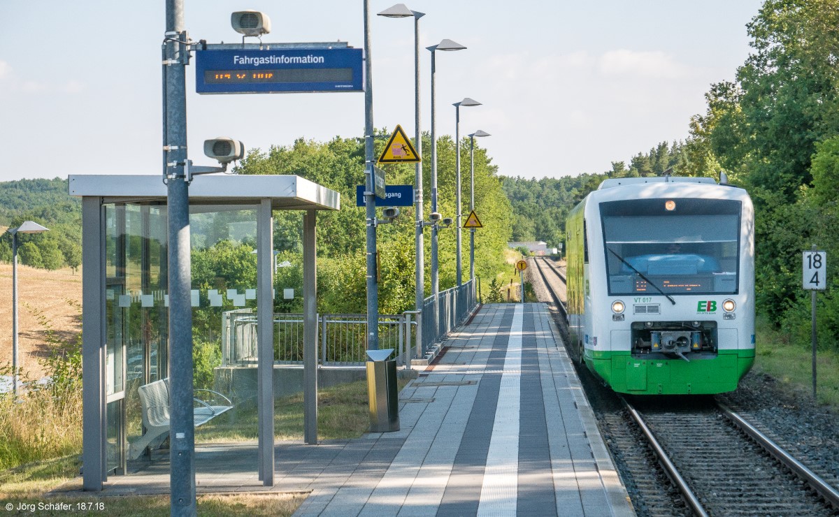 Der EB-VT 017 fuhr am 18.7.18 in den Haltepunkt Rottershausen ein. Links vom Triebwagen der Treppenzugang und rechts von ihm das km-Schild 18,4.