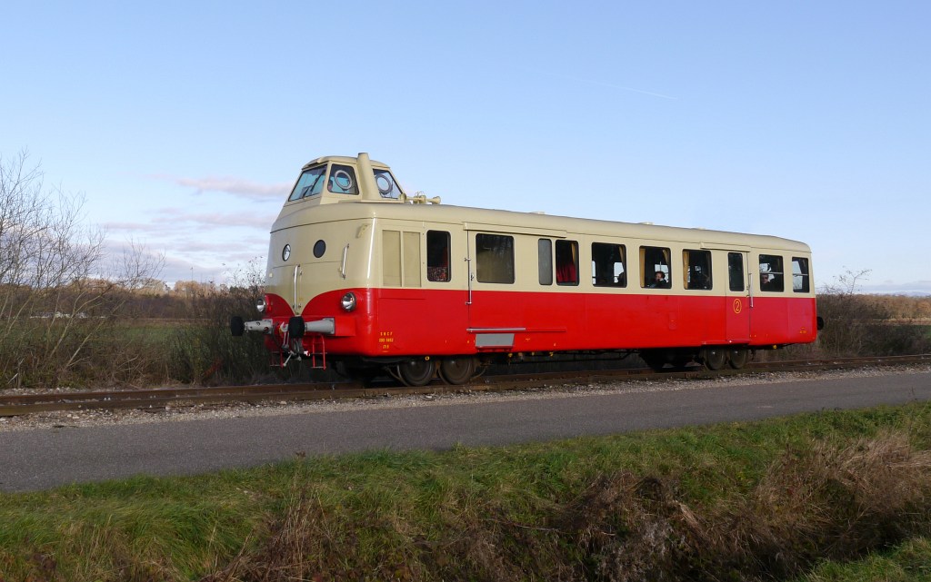 Der ehemalige SNCF Triebwagens X5852 vom Typ U-150 'Mobylette' unterwegs  bei Guewenheim auf der Dollertalbahn im Oberelsass. Hier gut zu sehen die eigentümliche Konstruktion des Fahrwerks dieser in der direkten Nachkriegszeit konstruierten Triebwagen. Sie besitzen  faux bogies , also  falsche Drehgestelle . Tatsächlich sind es unter dem Triebwagen keine Drehgestelle, sondern vier seitenverschiebliche Achsen.

2013-12-08 Guewenheim/Gewenheim