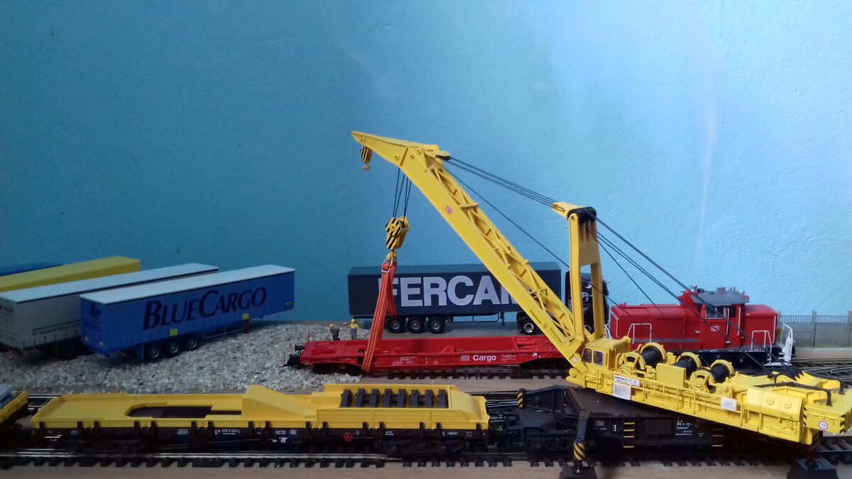 Der Eisenbahndrehkran mit dem Ausleger  in Aktion  beim Aufstellen eines Güterwaggons auf die Gleise (3.04.2022).