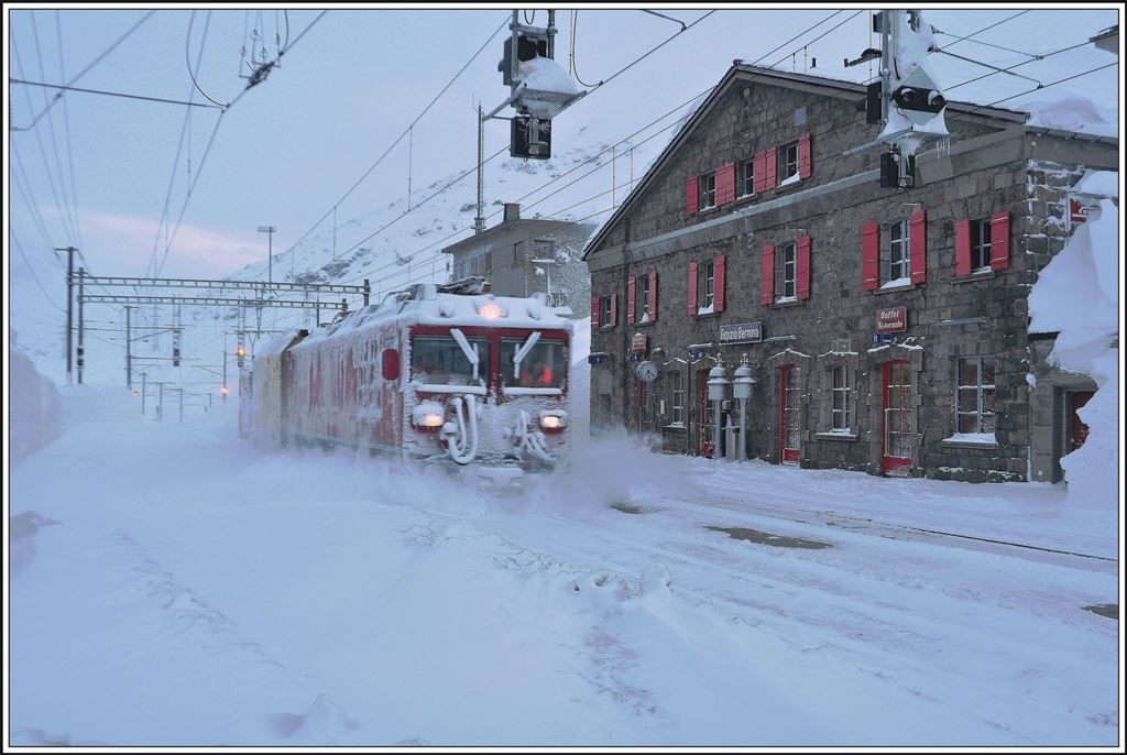 Der erwachende Tag in Ospizio Bernina zeigt viele Facetten. Auf der Durchfahrt nach Alp Grüm saust Gem 4/4 801 mit Xrot 95404 ohne Halt durch den Bahnhof. (22.02.2014)