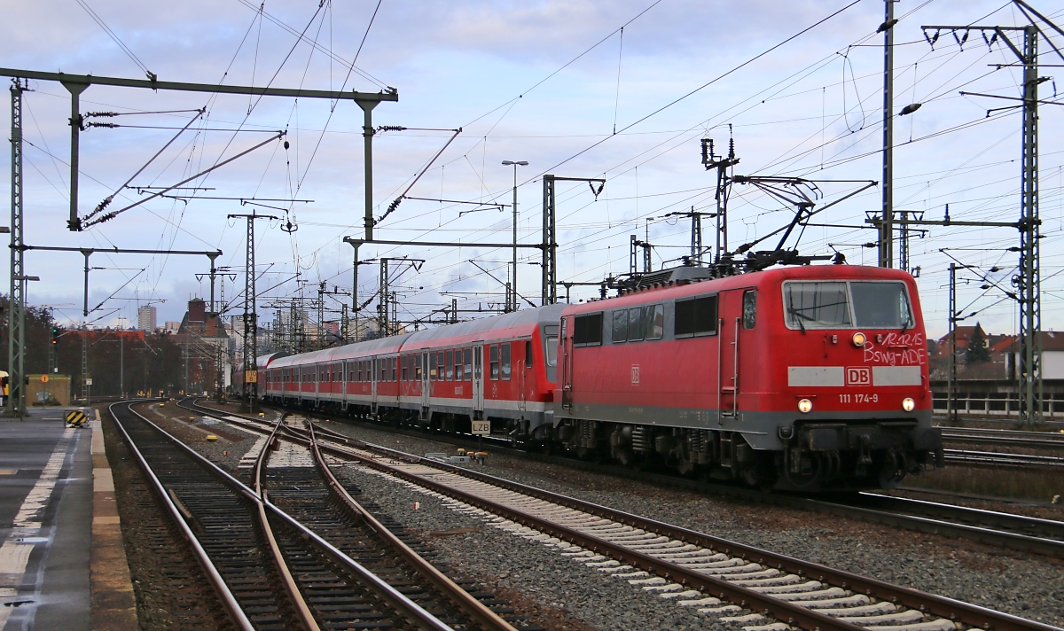 Der Fahrplanwechsel lässt grüßen. 111 174-7 mit der Aufschrift  BSWG Ade  und einer Menge Personennahverkehrs-Wagen als Überführung aus Braunschweig bei der Durchfahrt durch Fulda. Aufgenommen am 12.12.2015.