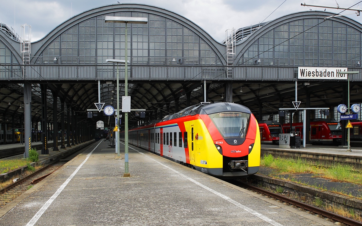 Der farbenfroh lackierte ET 163 der Hessischen Landesbahn fährt am 27.06.2023 mit einem Zug der RB 75 (Wiesbaden - Aschaffenburg) aus dem Wiesbadener Hauptbahnhof aus