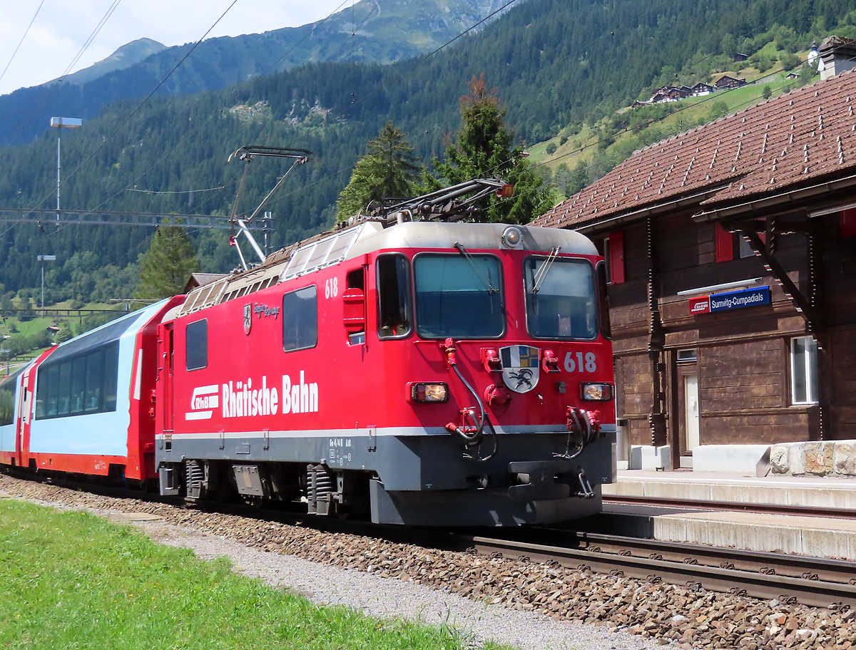 Der Glacier-Express von Zermatt nach St. Moritz durchfährt den Bahnhof Sumvitg-Cumpadials mit dem malerischen Bahnhofsgebäude. Somvix, 31.7.2023