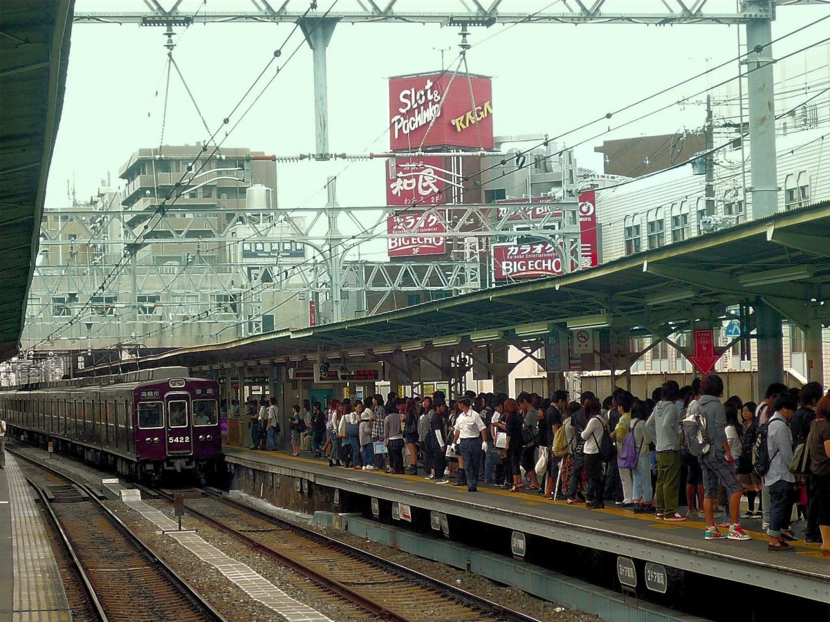 Der Hankyû-Konzern - die Züge der 1970er Jahre: Ôsaka ist ein Stadt voller Kontraste, von schönen Villen bis zu sehr dicht bebauten, eher ärmlichen Gebieten. Vor dem Hintergrund eines typischen  Bauchaos  fährt 8-Wagenzug 5321 (Endwagen 5422) in die Station Ôsaka-Awaji ein; 28.September 2009.