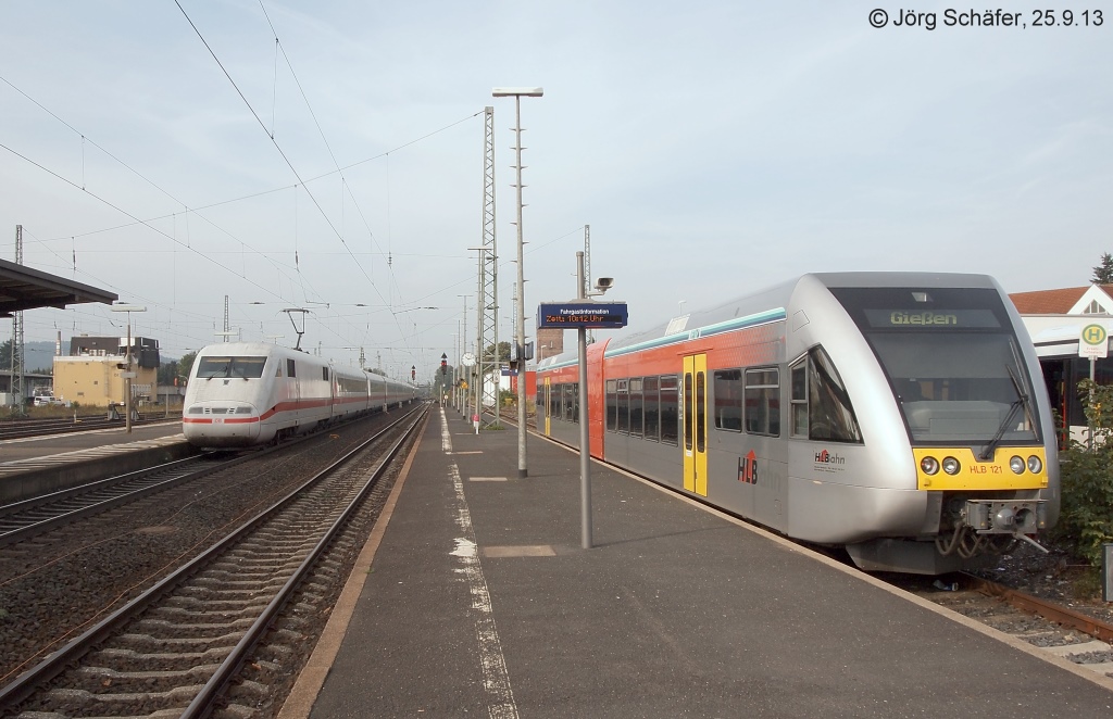 Der HLB-Triebwagen 121 wartet am 25.9.13 in Gelnhausen auf den „Zeigersprung“ f�r seine Abfahrtsminute. Ob die Fahrg�ste im durchfahrenden ICE nach Hamburg ihm wohl Beachtung schenken? 