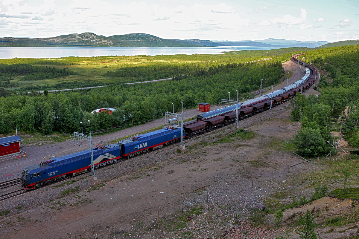 Der Ic 96 von Narvik kommend nach Stockholm,geführt von Lok Rc 6 1326 wird  umschlängelt  von einem vollem Erzzug,geführt von Björkliden 110 mit Lulea 103.Bild vom 20.7.2014 am Bahnhof Torne Träsk