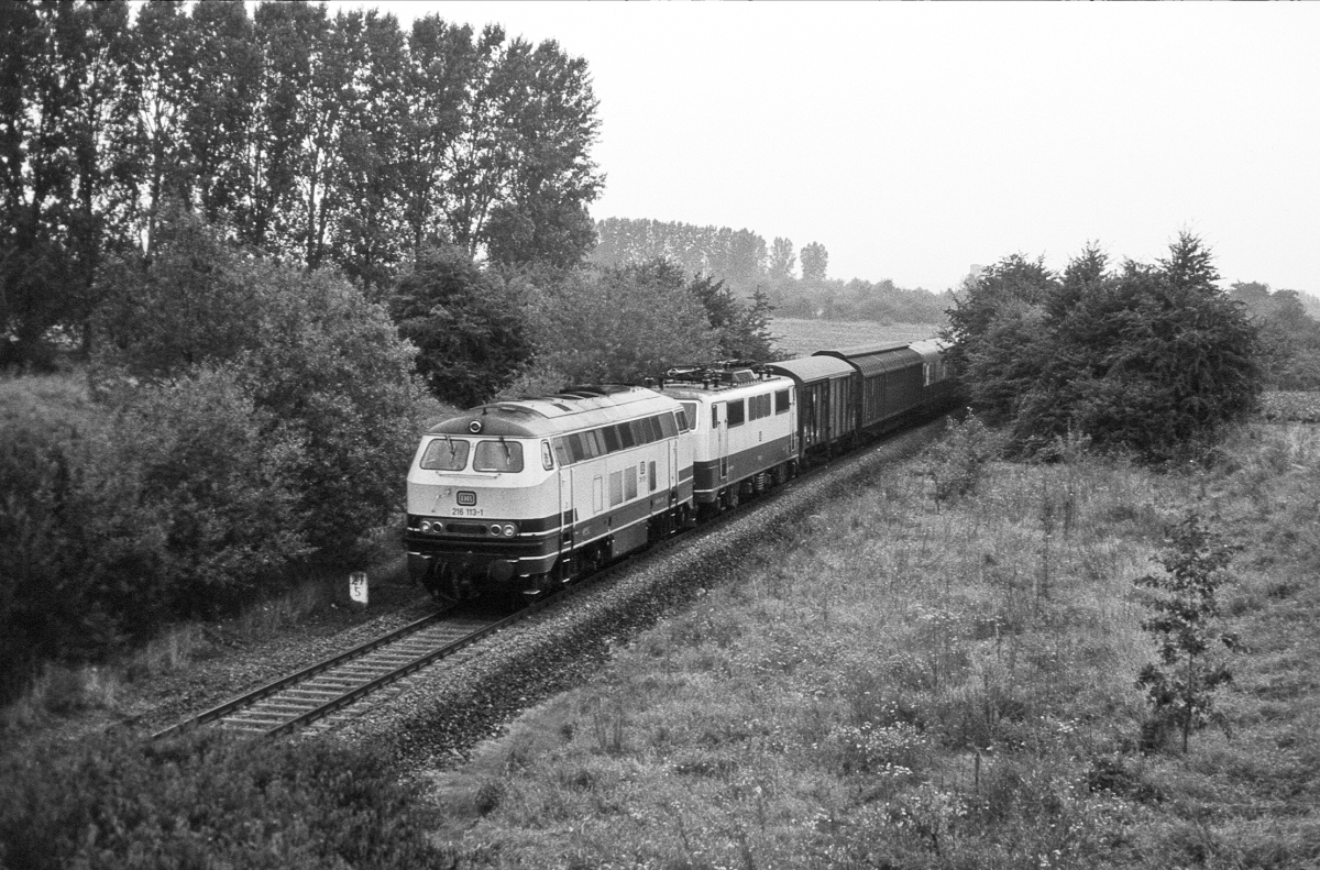 Der interessanteste Zug auf der eingleisigen Hauptbahn Friedberg - Friedrichsdorf war in den frhen 1980er Jahren ein ExprD (Expressgutzug) der werktags gegen 6 Uhr nach Frankfurt verkehrte. Um die Hauptstrecke Friedberg - Frankfurt ber Bad Vilbel im Berufsverkehr zu entlasten, wurde er mit Dieselvorspann ber Friedrichsdorf gefahren, wobei die planmige 111 abgebgelt mitlief und ab Friedrichsdorf wieder  an den Draht  ging. Im Juni 1982 ist die Gieener 216 113 vor 111 075 bei Rosbach unterwegs. Fr kurze Zeit nahm auch ein amerikanischer Militrzug Berlin - Frankfurt (mit 216 + 103 !) diesen Weg, aber so frh, das er nur bei Versptung zu fotografieren war, was mir nur einmal in schlechter Qualitt gelang.