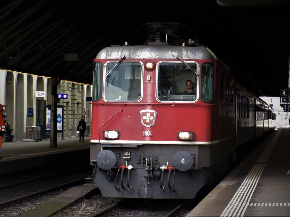 Der IR 2265 fuhr am 28.2.17 von Winterthur nach Wil SG- Gossau SG- St. Gallen. Im Bild trifft der IR 2265 auf Gleis 4 im Bahnhof Winterthur ein. Ausser die Lokfront der SBB Re 4/4 II Nr. 11164 sind alle Waggons vom IR im Schatten der Bahnhofshalle von Winterthur versteckt.