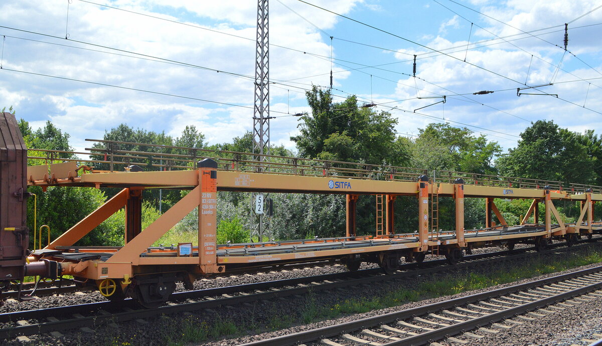 Der italienische Transportlogistiker für Fahrzeuge SITFA S.p.A. mit einer Wageneinheit für den Kfz-Transport in gelborange mit der Nr. 23 RIV 83 I-SITFA 4364 904-8 Laaeks (leer) in einem gemischten Güterzug am 05.07.22 Vorbeifahrt Bahnhof Dedensen/Gümmer.