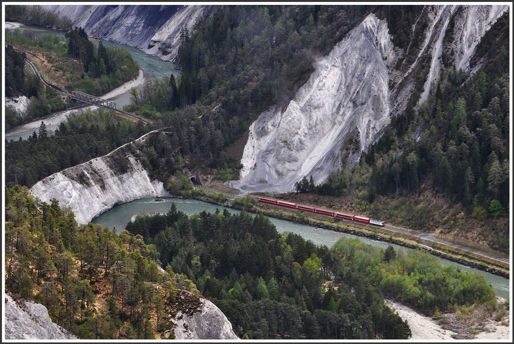 Der Kalksteinriegel zwingt den Rhein hier eine Schlaufe einzulegen. Der Wanderer wird gezwungen den Hügelzug auf steilem Weg zu überqueren. Den direkten Weg durch den Berg nimmt die RhB. RE 1232 mit Ge 4/4 II 616  Filisur  kurz vor Versam-Safien. (27.04.2015) 