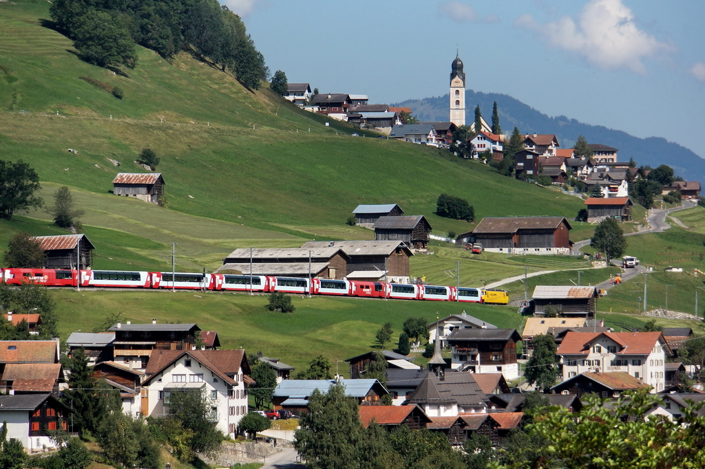 Der lange Glacier-Express mit der gelben Ge 4/4 III 644 in Richtung Chur. Im Hintergrund die Kirche von Sumvitg. Eigentlich wollte ich direkt an der Bahnlinie Fotos machen, aber durch Baustellen kam ich ab vom richtigen Weg. Mit einem 300 mm Teleobjektiv konnte ich doch noch ein paar Aufnahmen machen. 5.9.2013