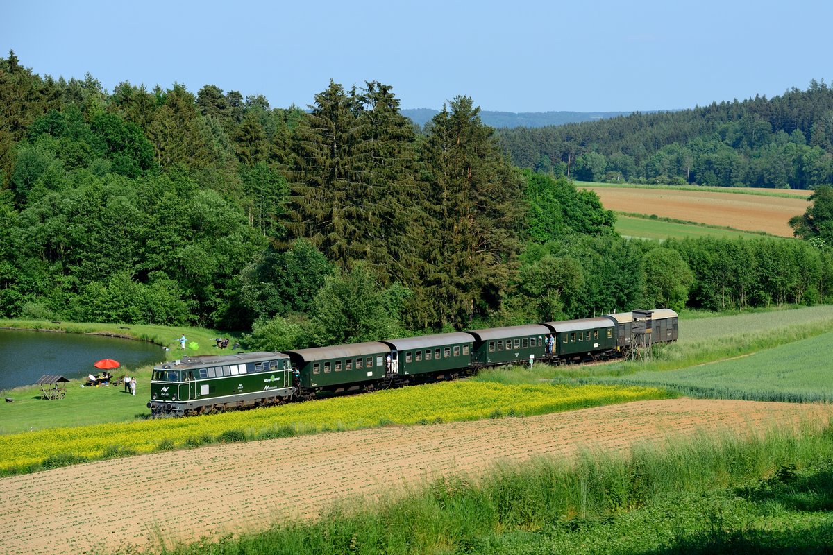 Der letzte Zug des Tages nach Drosendorf wurde am sogenannten Angerparadies bei Hessendorf abgewartet. Hier fährt der Reblaus-Express durch eine für das Waldviertel typische Szenerie: Erdäpfelfeld, dunkle Wälder und ein Fischteich. Einige der Reisenden genießen die Fahrt auf den offenen Plattformen der Spantenwagen (04. Juni 2015).