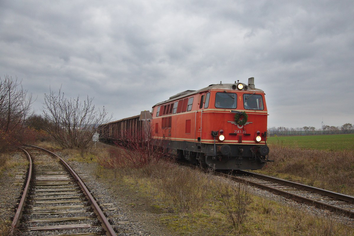 Der letzte Zug zwischen Mistelbach und Hohenau fährt gerade in den ehemaligen Kreuzungsbahnhof Dobersmannsdorf ein. Der Gleis auf der linken Bildseite führte einst nach Zistersdorf und von dort weiter bis nach Wien Stammersdorf.
Zuglok ist die 2143.35. (12.12.2015)