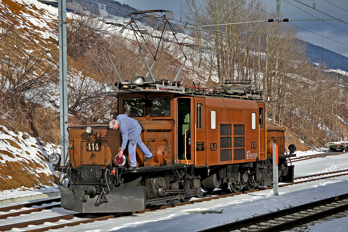 Der Lokführer entnimmt der Ge 6/6 I Nr.414 die rote Schlusslichtscheibe nach der Ankunft in Scuol am 24.1.2015