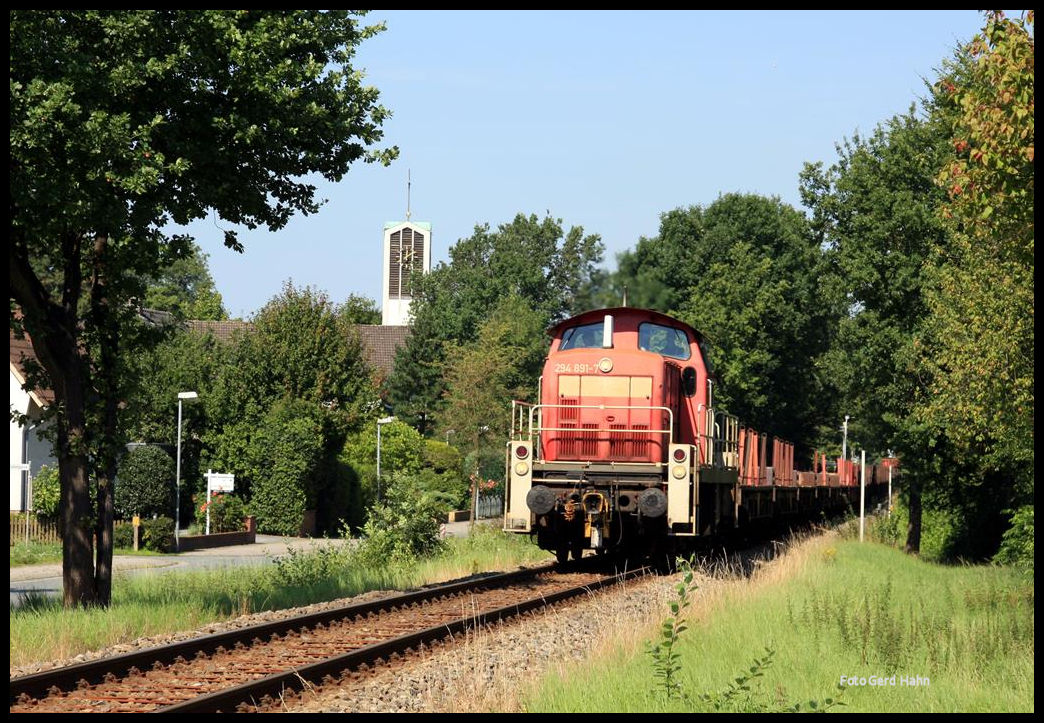 Der mittägliche DB Güterzug nach Georgsmarienhütte kommt hier am 14.8.2017 um 12.08 Uhr in Form der Osnabrücker 294891 in Hasbergen an der im Hintergrund sichtbaren katholischen Kirche Sankt Josef vorbei.