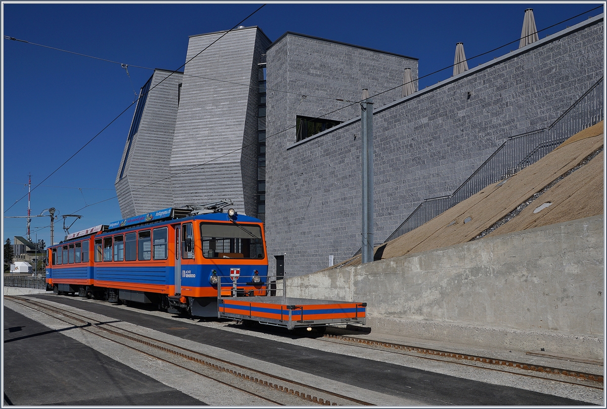 Der Monte Generoso Bhe 4/8 N° 11 mit seinem Vorstellwagen von der dem Hintergrund der   aufgeblühten  Steinblume von Mario Botta.
21. Mai 2017 
