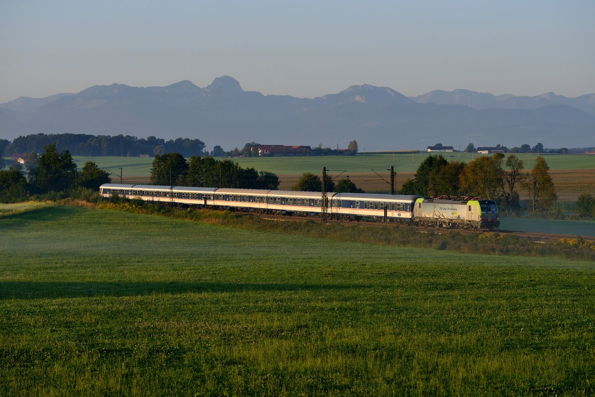 Der morgendliche M 79060 von Kufstein nach München HBF steht momentan bei Eisenbahnfreunden hoch im Kurs, kommt hier doch die NX-Wagen-Garnitur als Ersatz für einen Meridian-Triebzug zum Einsatz. Am 30. August 2017 wollte ich die vermutlich letzte Chance nutzen, den Zug bei Tageslicht bei Haus zu dokumentieren - die Tage werden zu dieser Jahreszeit schon merklich kürzer. Gespannt wartete ich darauf, welche Maschine aus dem Fahrzeugpool von Lokomotion diesmal zum Einsatz kommt. Es war mir erneut nicht vergönnt, eine Schaltwerk-Lok vor dem Zug zu fotografieren. Aber die 475 404 von der BLS war mehr als nur eine nette Entschädigung. Im Jahr 2017 war diese Lok zeitweise für Lokomotion im Einsatz. Hintergrund: Das Münchner Unternehmen hatte an die BLS einige Loks der Baureihe 186 verliehen, die auf der Rheinschiene zahlreiche Kilometer anhäuften. Zur Kompensation kam nun der in der Schweiz beheimatete Vectron für Lokomotion zum Einsatz. Im ersten Morgenlicht kam die attraktive Farbgebung dieser Maschine gut zur Geltung.