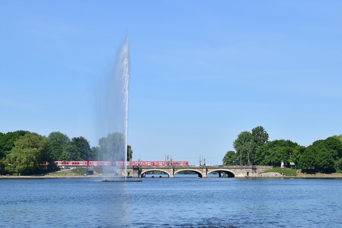 Der Motivklassiker in Hamburg schlecht hin. Ein Blick über die Binnenalster auf die Lombardsbrücke und die dahinterverlaufende Bahnstrecke Hamburg Hbf Hamburg Altona/Diebsteich. Ein Zug der Baureihe 474 überquert gerade die Alster auf den Weg zum Hamburger Hbf.

Hamburg 13.05.2025