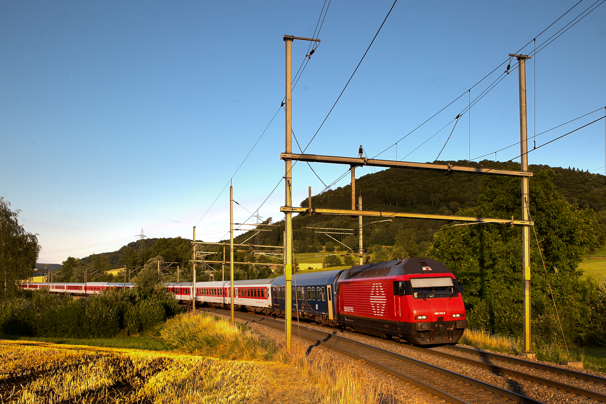 Der Nachtzug von Zürich HB nach Prag braust mit der Re 460 110-0 im abendlichen Licht in Frick vorüber.Bild vom 9.7.2015