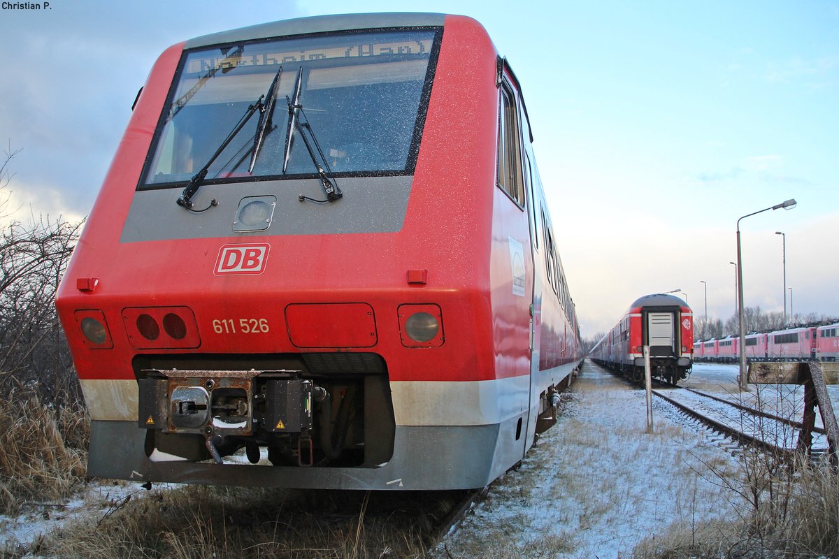 Der Pannolino (dt. Windel), abgeleitet aus dem Vorgängermodell VT 610  Pendolino , hatte als rein  Deutsches  Fabrikat seine Schwierigkeiten sich gegenüber dem  Italiener  zu behaupten, da er mit im Militär verwendeter Technik ausgestattet war, die damals wie heute sehr Fehler belastet ist.
Der 95 80 0611 026-5 D-DB/95 80 0611 526-4 D-DB ist einer von nur rund fünfzig VT 611 (Verbrennungstriebwagen mit Neigetechnik) die gebaut wurden, bis der Großauftrag der Bundesbahn storniert wurde. Seit dem 15.12.15 ist nun das Stillstandsmanagement der DB die letzte Heimat der Neigetechnik Flotte.
Die zuletzt im Bw Ulm bei der DB ZugBus Regionalverkehr Alb-Bodensee GmbH beheimateten 16 Triebzüge der Baureihe 611.0 die im SSM Mukran stehen, haben in den Zug Ziel Anzeigen (ZZA) Northeim (Han) und Itzehoe stehen.
leider wird ein Teil der Triebwagen von Mukran aus nurnoch eine Reise antreten, wenn sie nicht vor Ort zerlegt werden.
Auffällig ist, das Verbrennungstriebwagen mit Neigetechnik bei der DB keine große Karriere zu erwarten haben.
Der 611 als zeite Neigetechnik Baureihe der Bundesbahn hat noch gut 21 Jahre sich behaupten können.
Die VT 612 werden in absehbarer zeit das Selbe schiksahl erleiden, und die ICE TD (Baureihe 605) hat nach Verhältnismäßig kurzer Betriebszeit ein Kaotisches Ende (bei der DB) ereilt.
Hoffentlich werden die verbleibenden  Muhikaner  noch eine Weile fahren.

(Kein Gleisbereich, vom Gehweg aus Fotografiert)