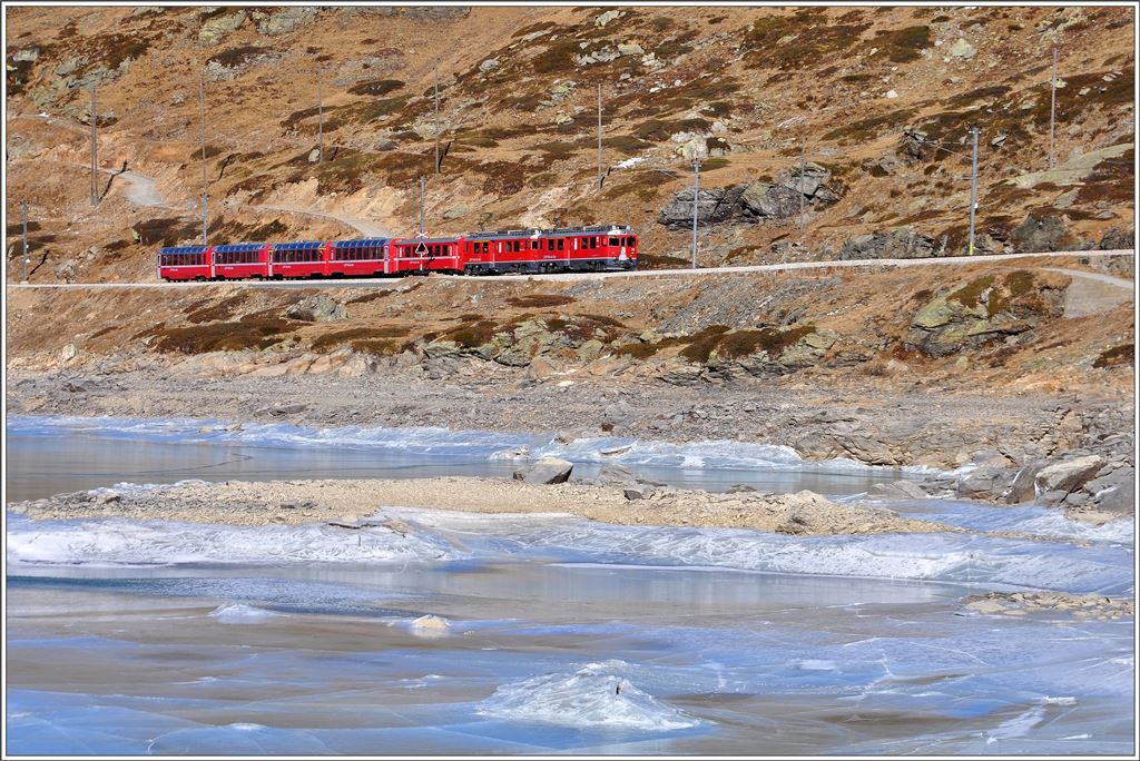 Der R1625 mit den beiden ABe 4/4 III 54  Hakone  und 55  Diavolezza  und den Wagen des Bernina Express ab Chur schlängelt sich dem gefrorenen Lago Bianco entlang.(10.12.2015)
