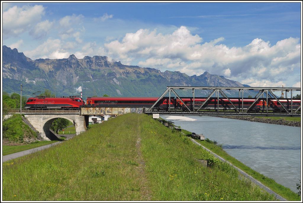 Der Railjet 165 überquert die Grenze zwischen der Schweiz und dem Fürstentum Liechtenstein auf der Rheinbrücke bei Buchs SG. Im Hintergrund ist die Alpsteinkette zwischen der Saxerlücke und dem Hohen Kasten zu sehen. (08.05.2014)
