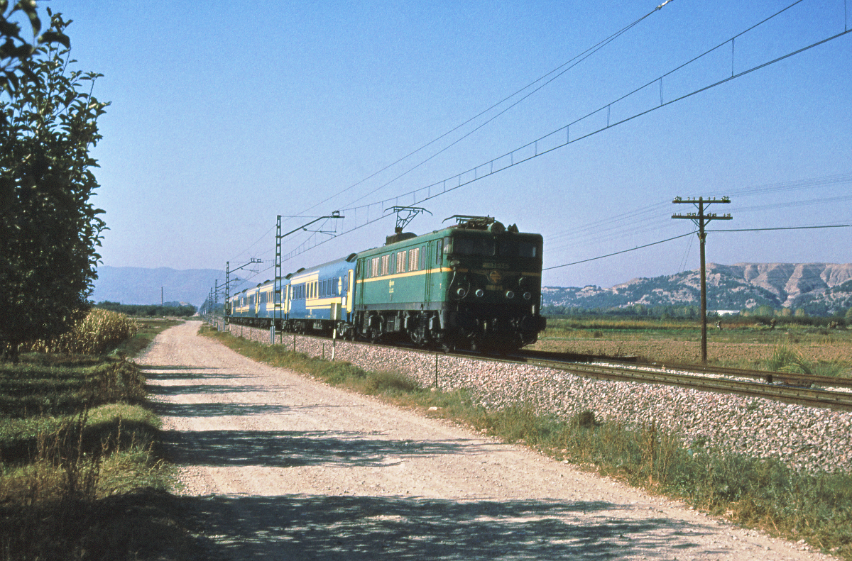Der Rapido 574 Madrid Chamartin - Zaragoza - Tarragona - Barcelona Sants fährt durch das Tal des Jalon, geführt von der grünen 269 053. Sein nächster Halt um 11.58 ist Calatayud. Über der fruchtbaren Ebene des Jalon erheben sich kahle Berge, dieser abrupte Übergang hat mich stets fasziniert. Als in den 70er Jahren die Strecke erneuert und schließlich elektrifiziert wurde, wurde einfach das neue Gleis neben das alte gelegt. 1983 war auch der zweigleisige Ausbau Madrid - Calatayud schon weit fortgeschritten. Oktober 1983.
Canon AE1, Canoscan, GIMP  
