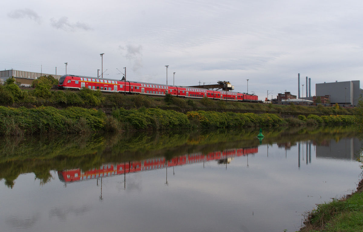 Der RE Saarbrücken - Koblenz hat den Bahnhof Völklingen verlassen und passiert das Brammenlager der Saarstahl AG. Direkt zwischen Saar und Werksgelände verläuft die Bahnstrecke 3230 Saarbrücken - Karthaus. 21.10.2013