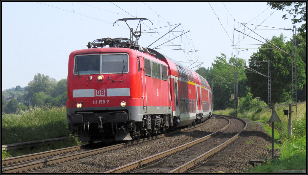 Der RE4 (Wupper Express) ist hier am Bahnübergang von Rimburg zu sehen. Als Zugpferd kommt die 111 158-2 zum Einsatz. Szenario vom 12.Juni an der Kbs 485 unweit der deutsch-niederländischen Grenze.