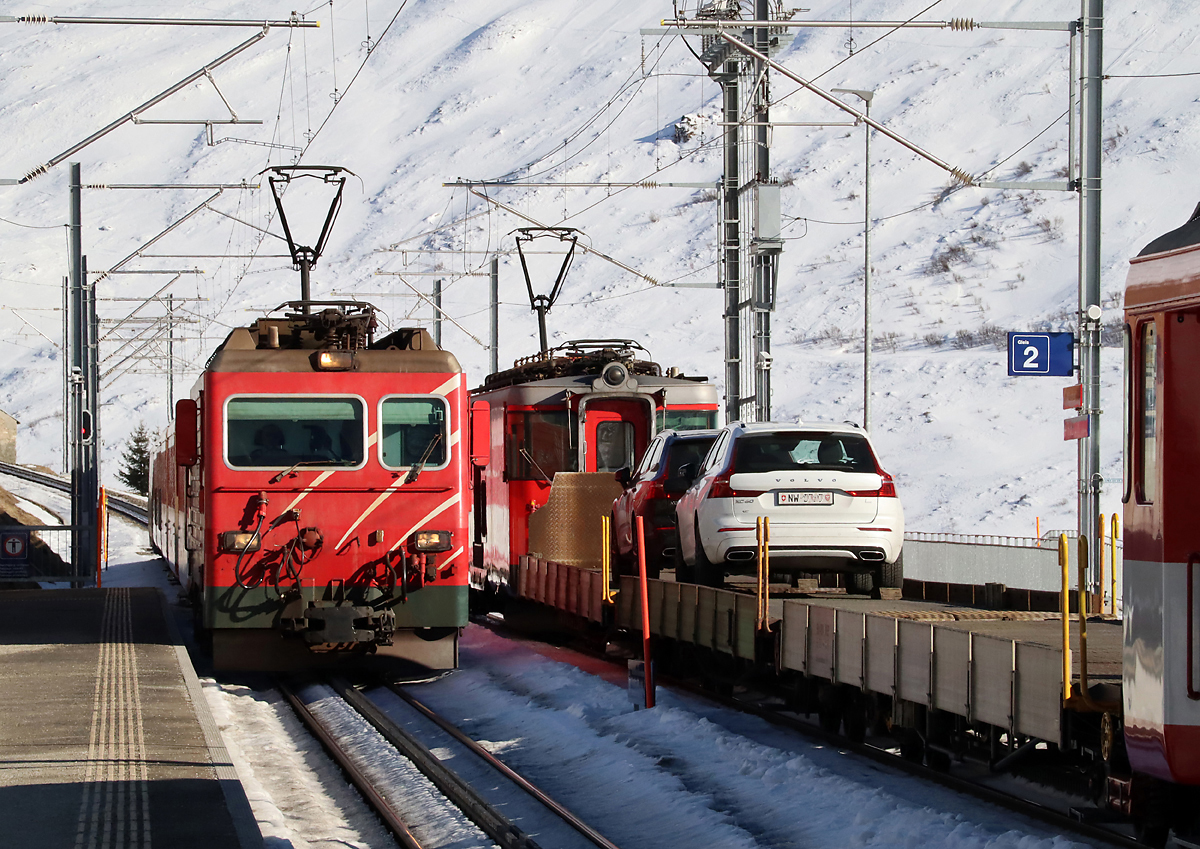 Der Regionalzug von Disentis nach Andermatt fährt in die Station Nätschen (1825 müM) ein, rechts wartet der Autozug von Andermatt nach Sedrun die Einfahrt des Regionalzuges ab. Die Autozüge wurden nach der Wintersaison 2022/23 endgültig eingestellt. Andermatt, 13.2.2023