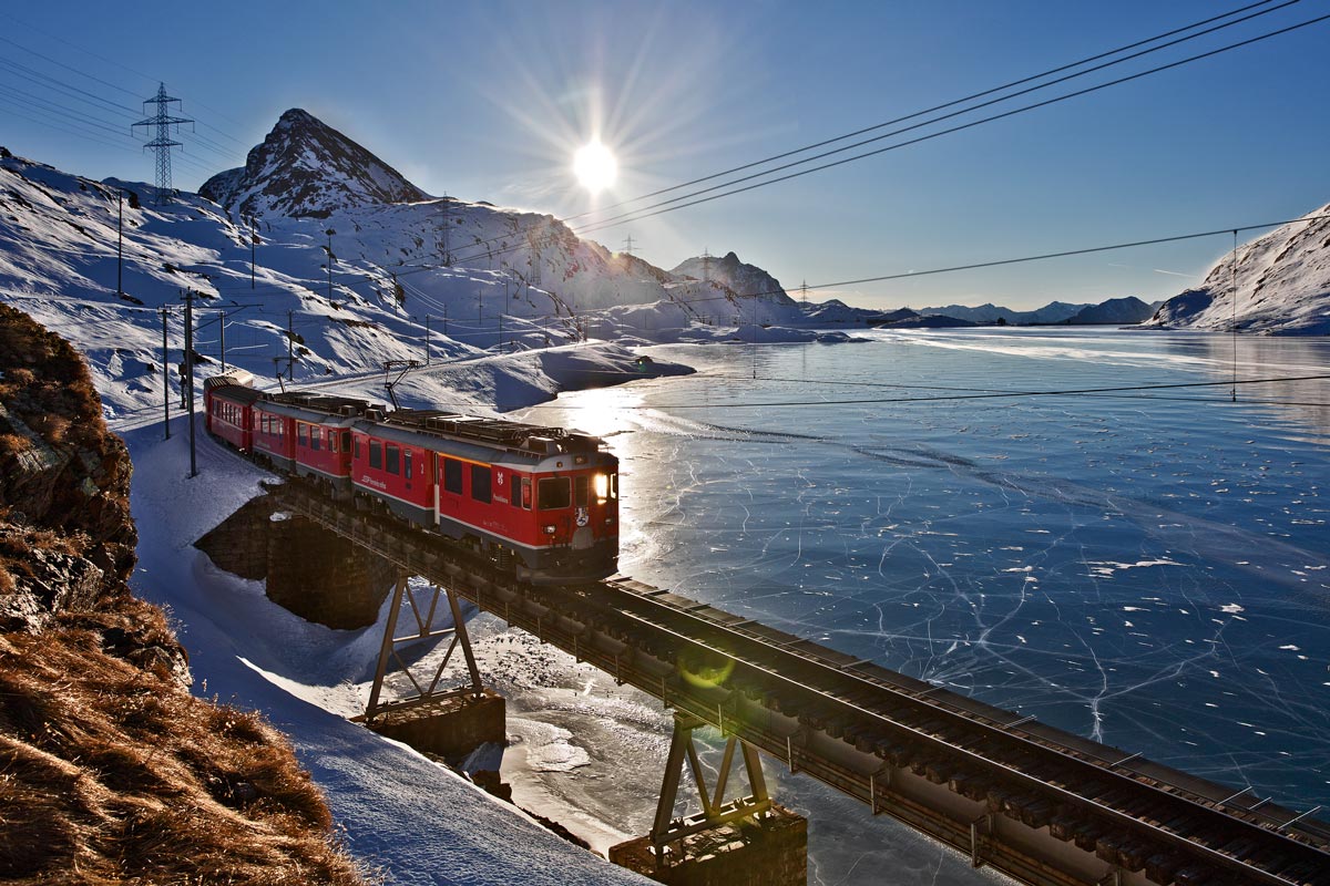 Der RhB Triebzug ABe 4/4 III Nr.51  Poschiavo  und Nr. 52  Brusio  fahren mit einem R am schwarzgefrorenen Lago Bianco entlang.Nild vom 28.12.2016 