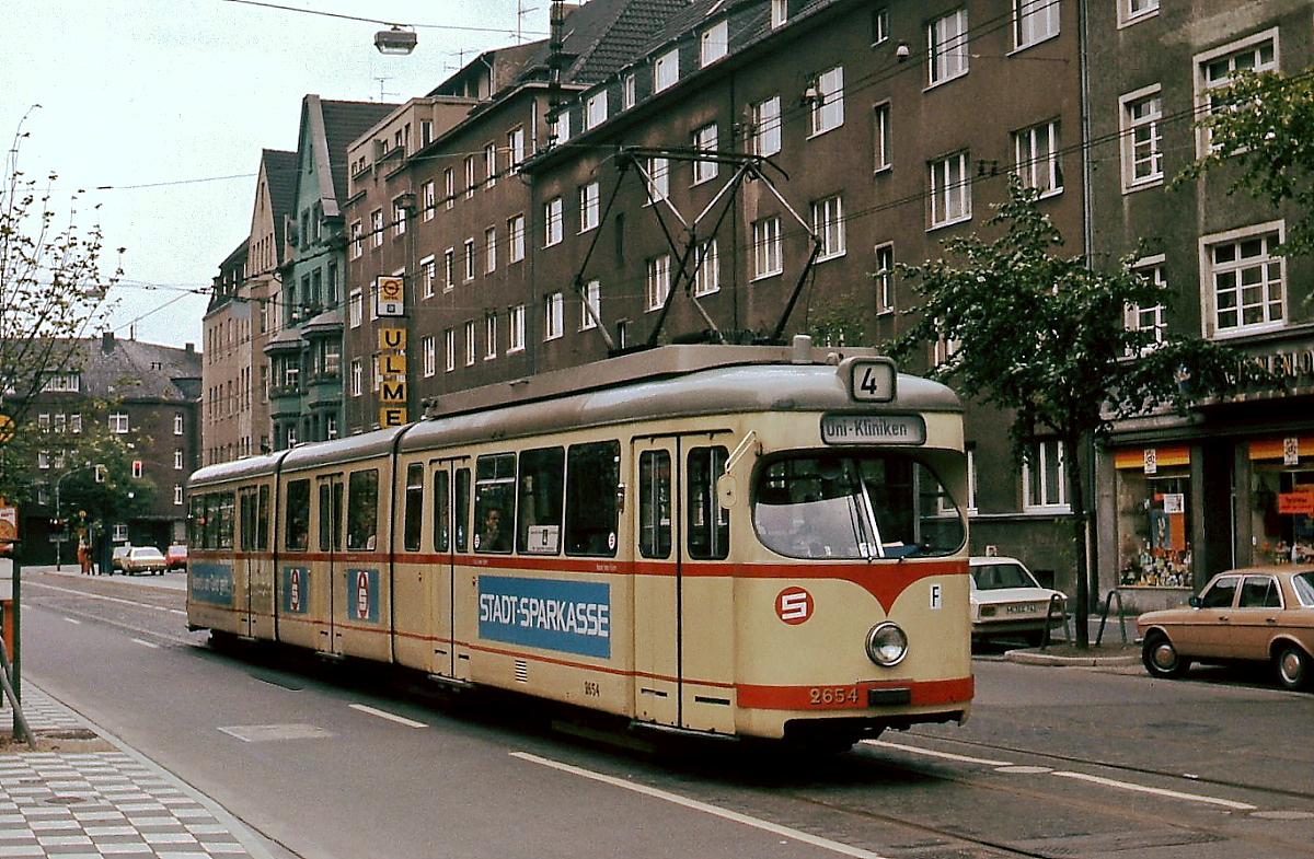 Der Rheinbahn-GT 8 2654 fährt in der zweiten Hälfte der 1970er Jahre von der Haltestelle Karolinger Platz in Richtung Uni-Kliniken ab