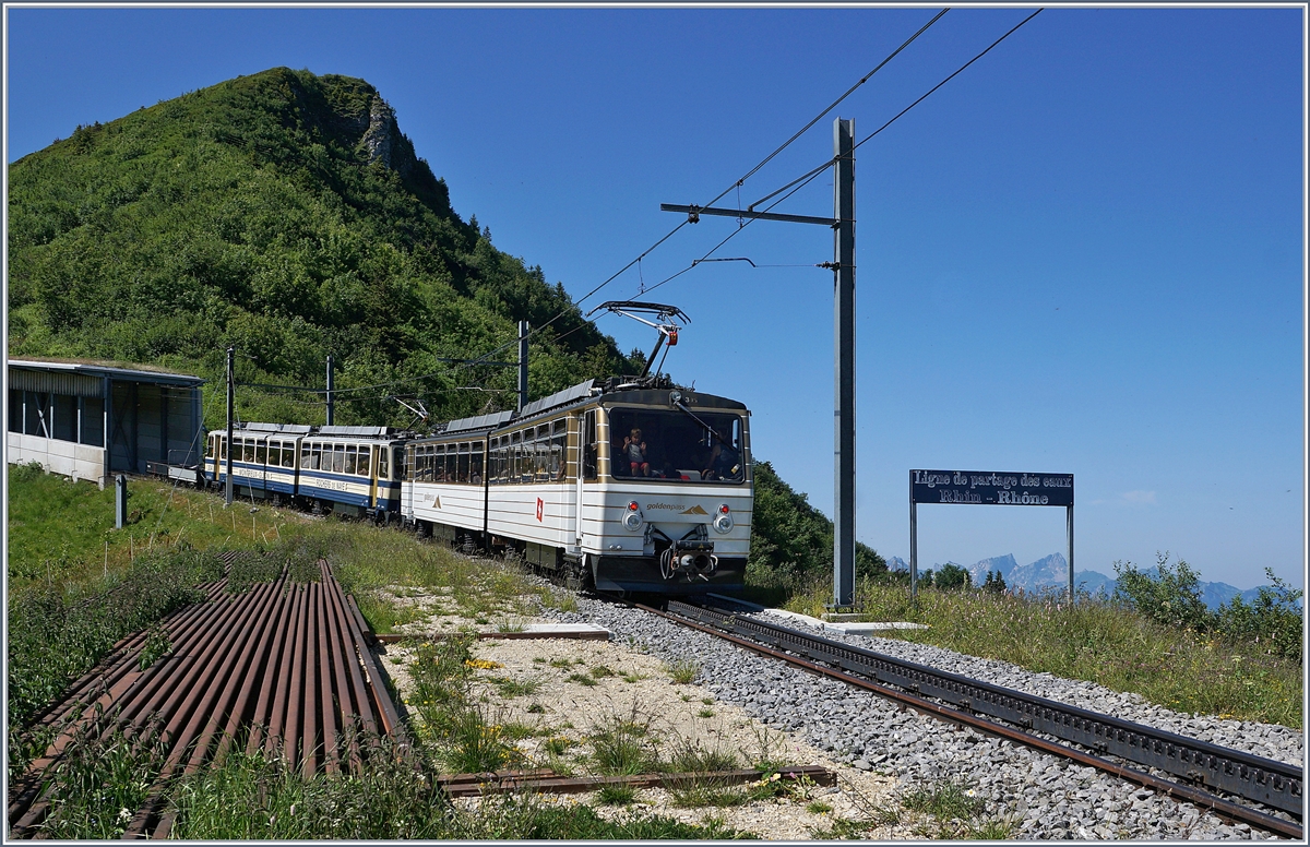 Der Rochers de Naye Beh 4/8 305 und ein weiterer sind auf dem Weg zum Rochers de Naye und passieren kurz nach dem Bahnhof von Jaman die Wasserscheide zwischen Rohne und Rhein.

1. Juli 2018