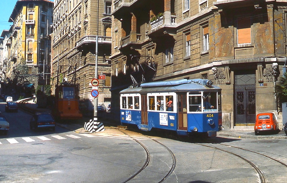 Der im Schatten stehende Standseilbahnwagen 2 hat gerade Tw 404 der Trenovia di Opicina zur Talstation an der Piazza Scorcola gebracht, der Triebwagen setzt jetzt seine Fahrt in Richtung Piazza Oberdan fort (Sommer 1981)