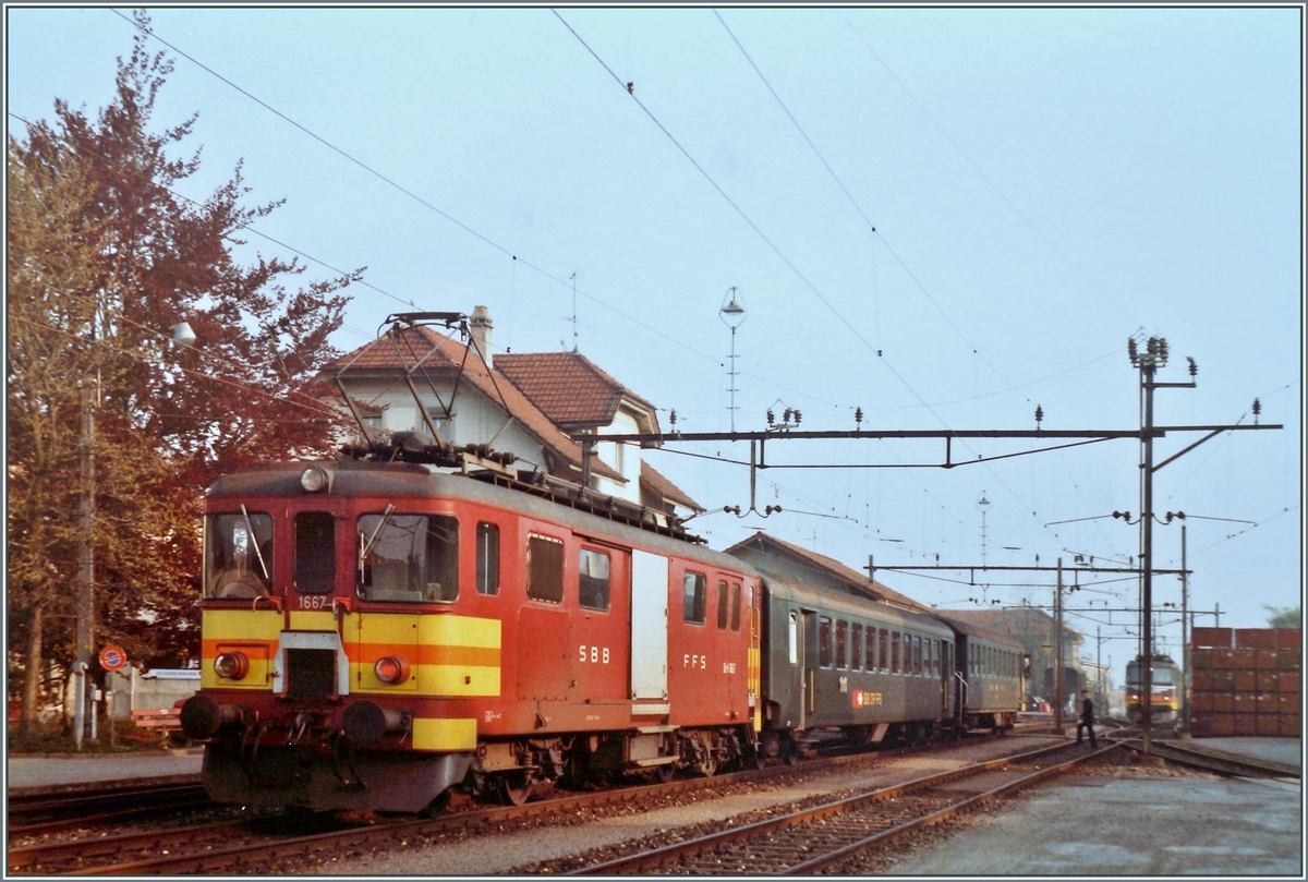 Der schiebende SBB De 4/4 1667 wartet mit seinem Regionalzug 6110 von Beromünster nach Beinwil am See im Bahnhof von Menziken SBB auf die Weiterfahrt.

Im Hintergrund ist eine rangierende Ae 6/6 zu erkennen.

15. Mai 1984